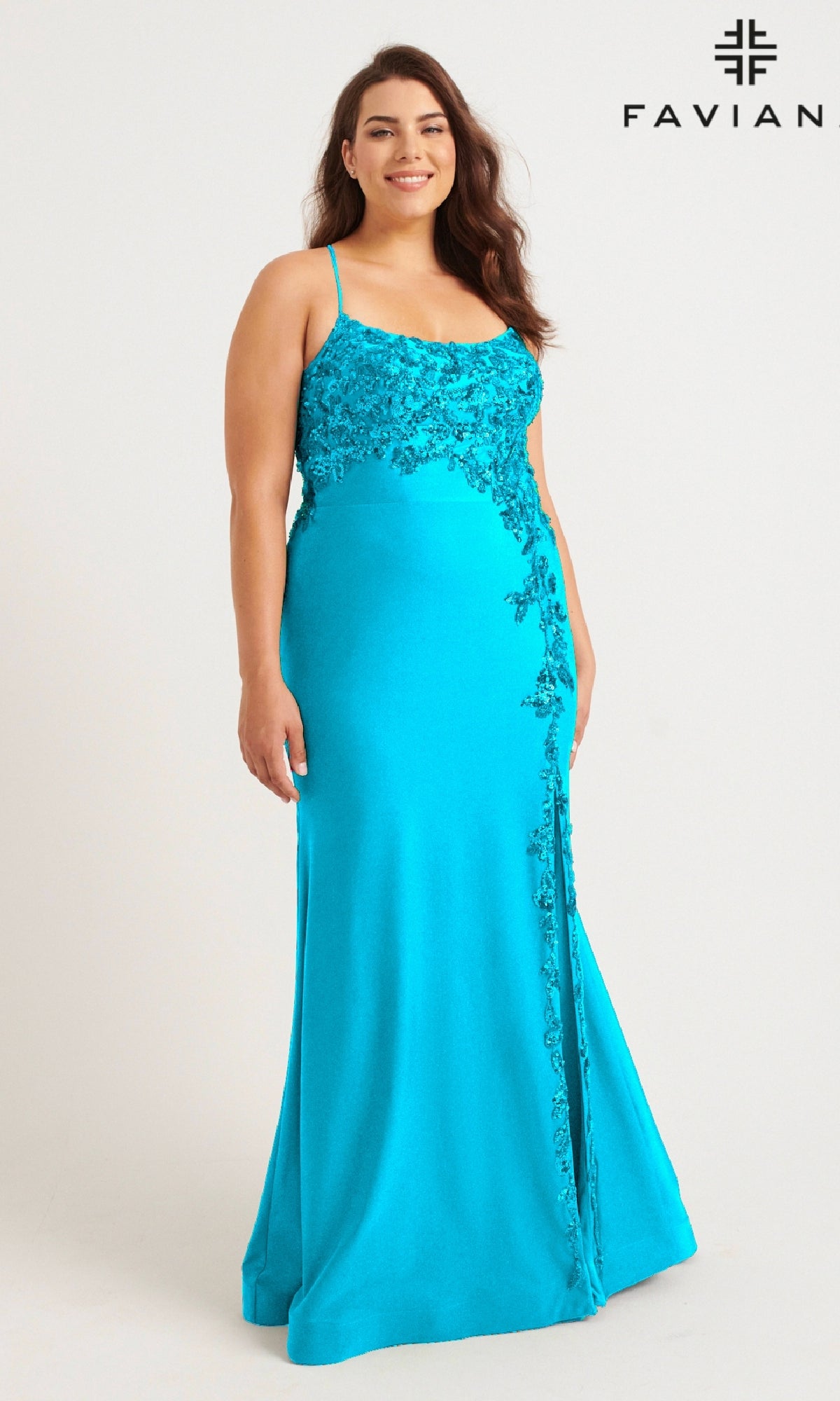 A woman wears the Faviana 9570 Plus-Size Strappy Long Prom Dress in bright turquoise with lace and sequin floral details, featuring thin straps and a fitted silhouette, standing against a plain white background.